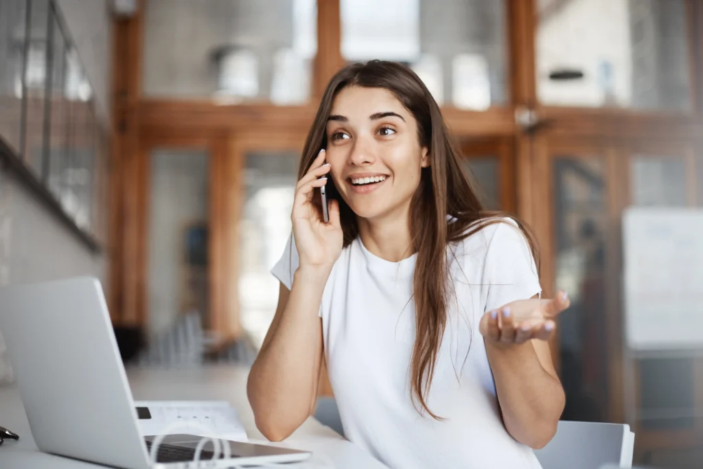 Jeune femme heureuse travaille au téléphone